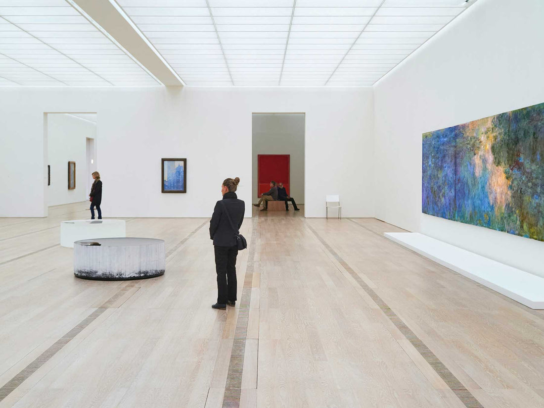 A spacious museum gallery with a wooden floor and a large landscape painting