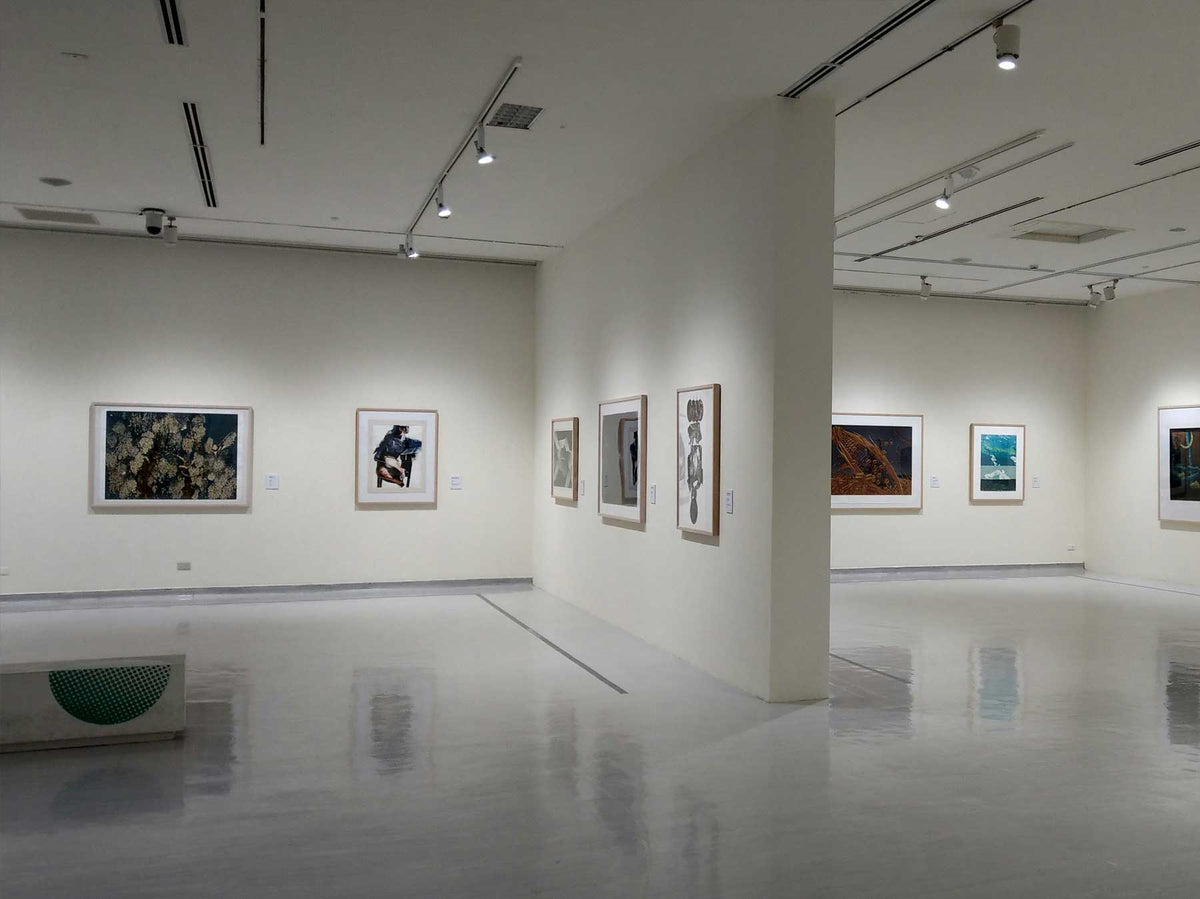 A pale minimal gallery corridor with works hung at intervals