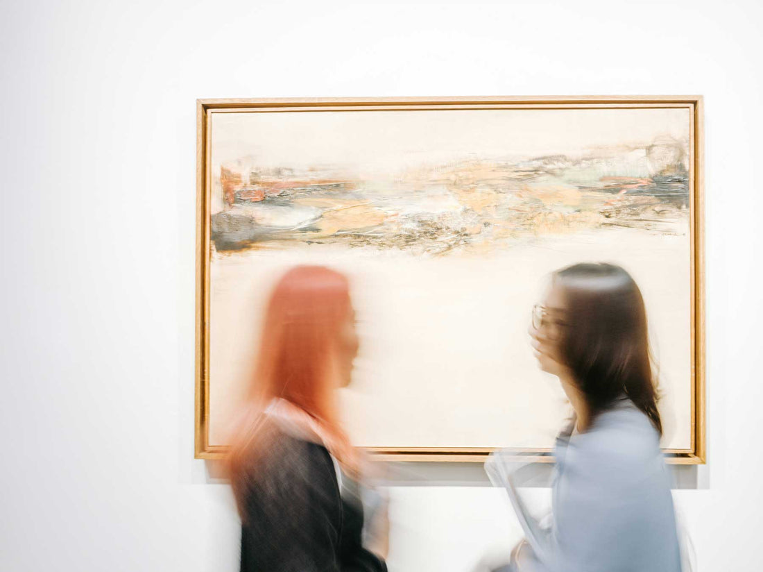 Two people examining a large framed landscape painting closely