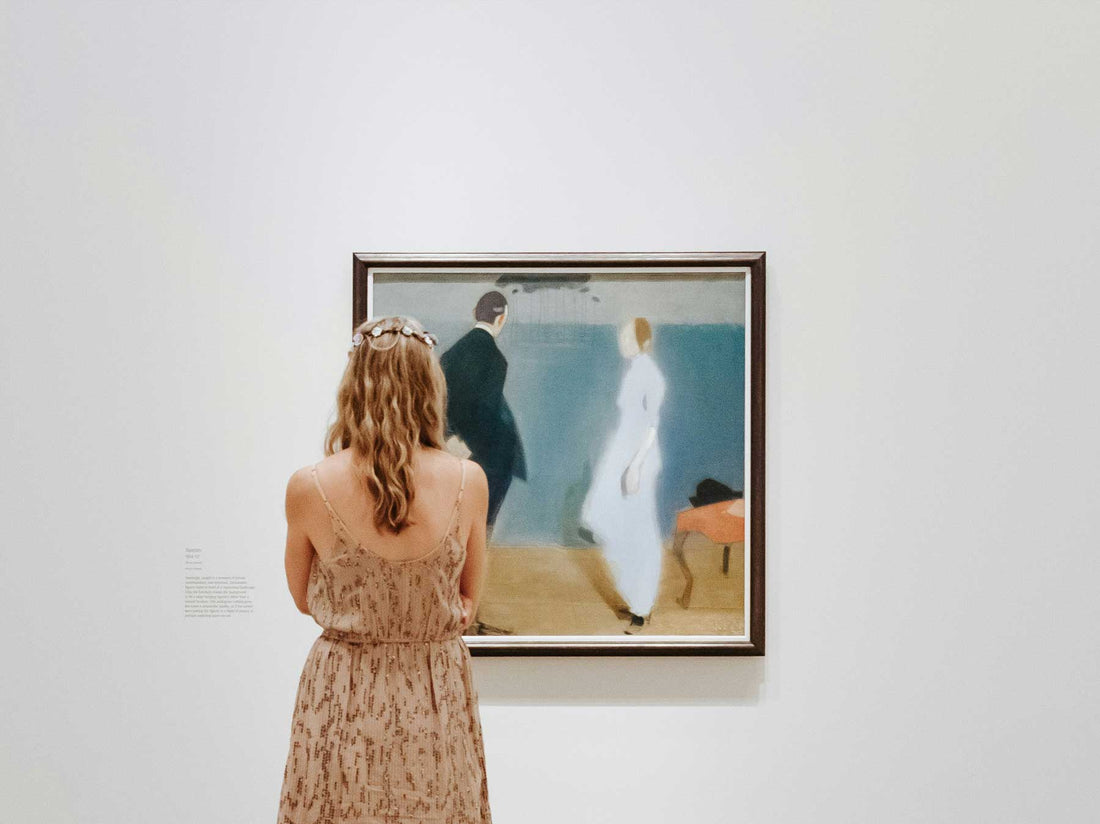 A visitor standing before a framed painting, considering it