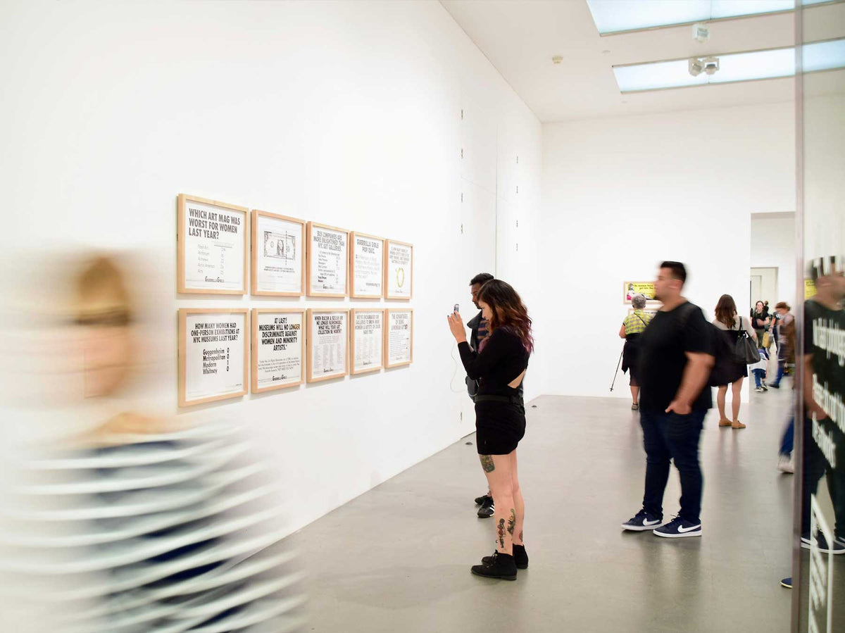 Visitors moving through a busy white-walled exhibition space